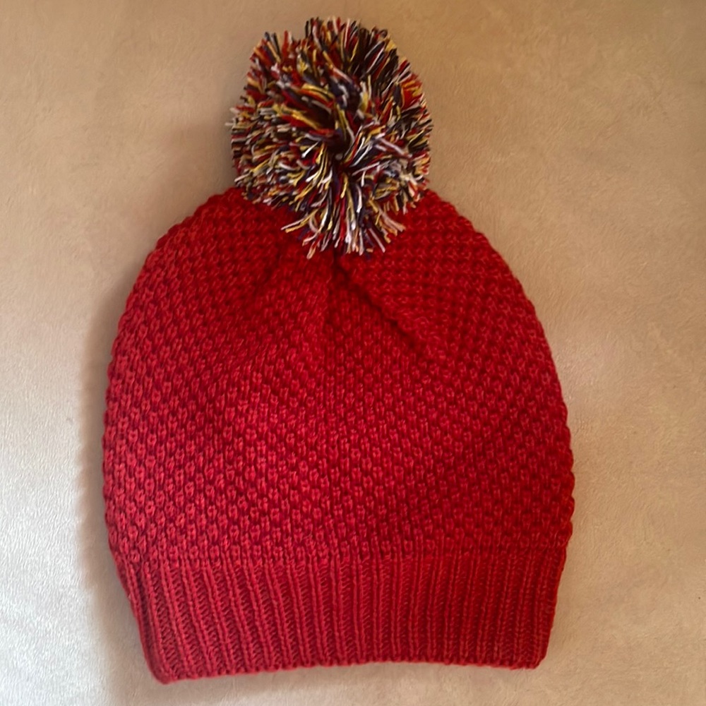 Red woven beanie, multi-color yarn puff.